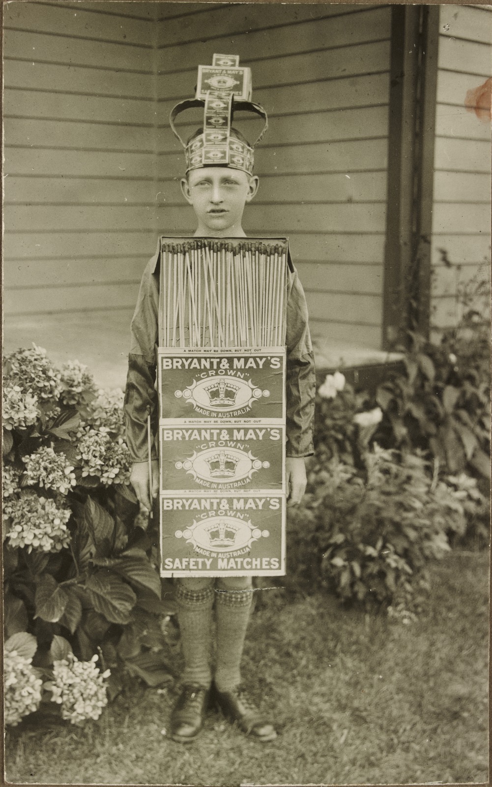 Shows boy in costume depicting Bryant & May's Crown Safety Matches.